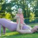 A mother in activewear exercises with her baby in a sunny park, promoting a healthy lifestyle.
