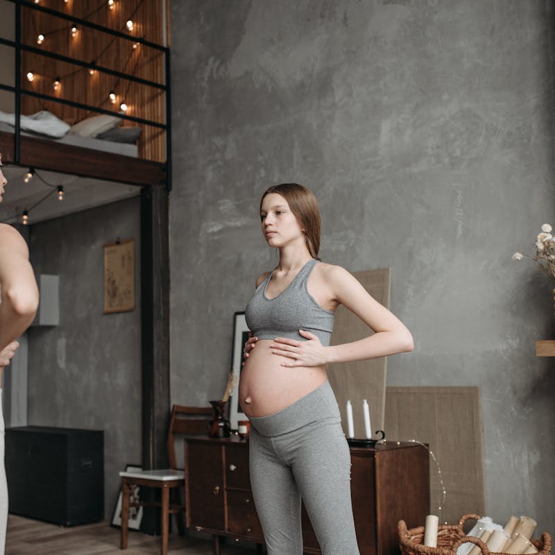 Expectant mother practicing prenatal yoga with guidance in a cozy home setting.