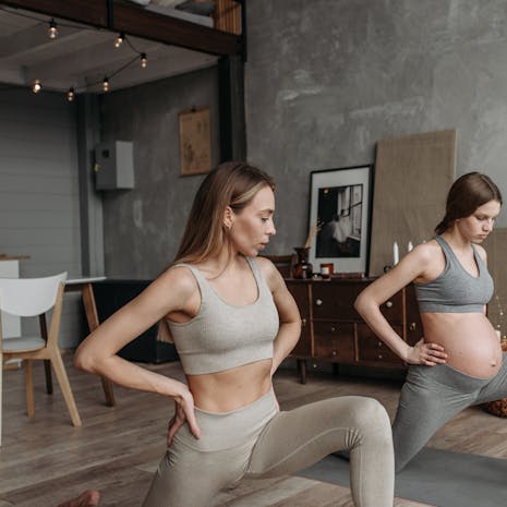 תמונה מאת Pavel Danilyuk Two pregnant women performing yoga indoors, promoting a healthy lifestyle through exercise.